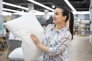 Free photo a young woman chooses a pillow in a home improvement store
