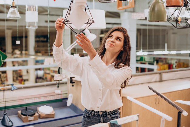 Young woman choosing chandelier in building center