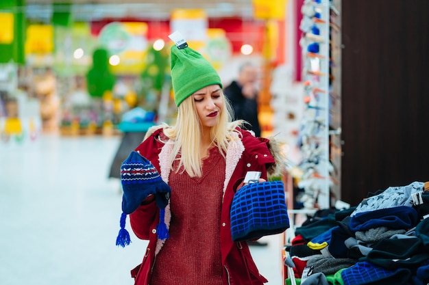 Free photo young woman choosing hat in shopping center