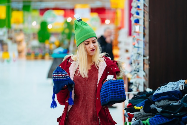 ショッピングセンターで帽子を選択する若い女性