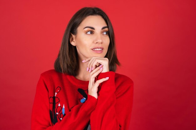 Young woman in a Christmas sweater   smiles pertly, excitedly, in anticipation of the holiday