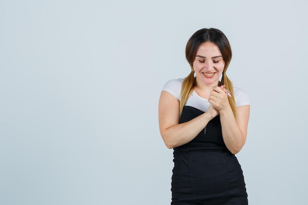 Young woman clasping hands and looking cheerful