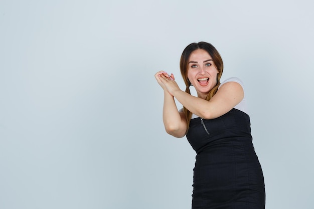 Free photo young woman clasping hands and looking happy