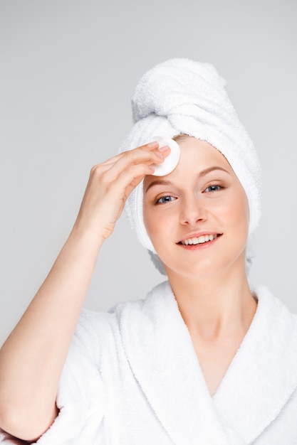 Молодая женщина очищает лицо после макияжа