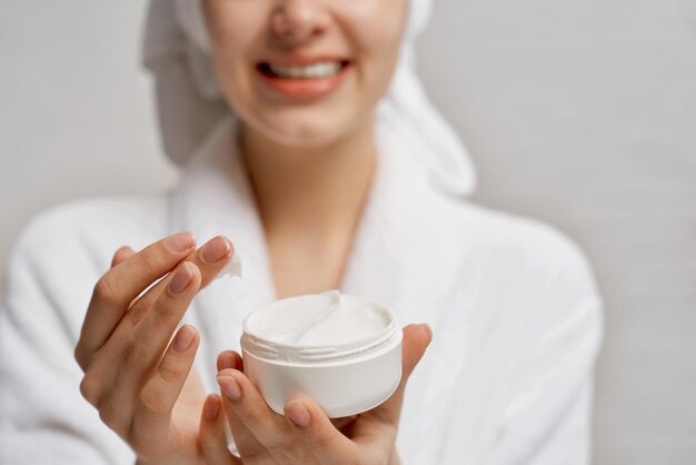 Young woman close up holding moisturizer and demonstrates