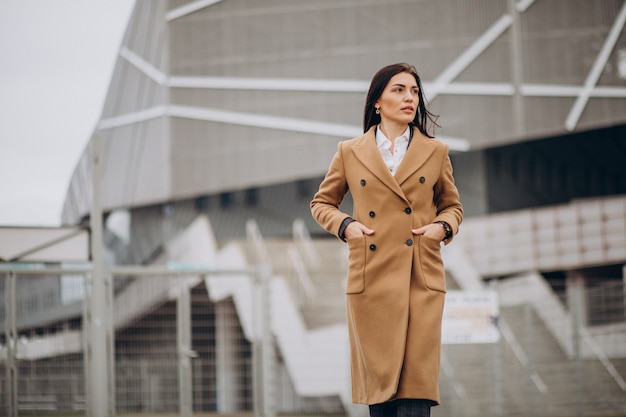 Young woman in coat standing outdoors