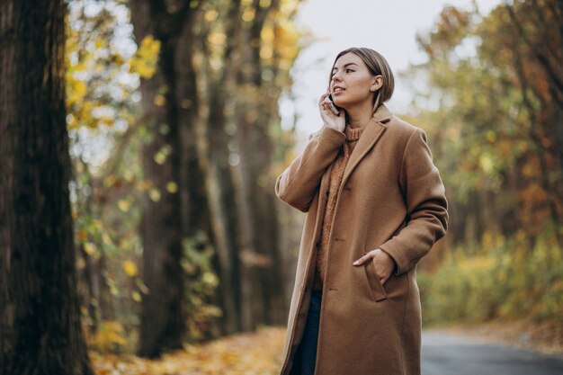 Young woman in coat standing on the road in an autumn park