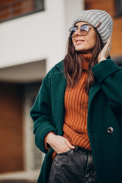 家で冬時間のコートの若い女性