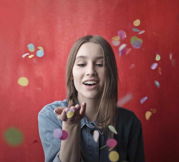 Free photo young woman collects some confetti that are falling