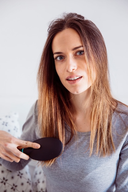 Foto gratuita giovane donna che pettina i capelli