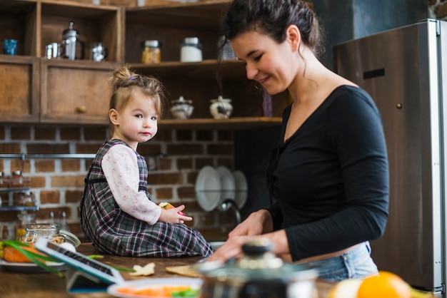 Young woman cooking near daughter