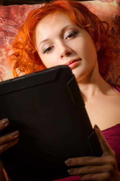 Free photo young woman on a couch with tablet pc