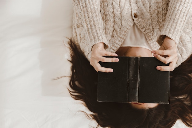 Free photo young woman covering face with book