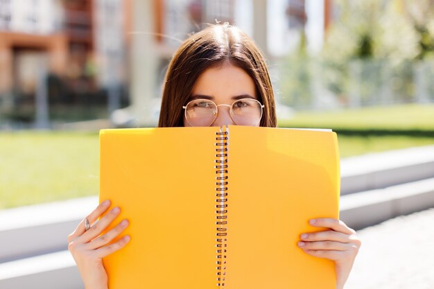 Young Woman covering her face with a notebook outdoors