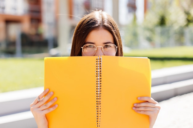 Young Woman covering her face with a notebook outdoors