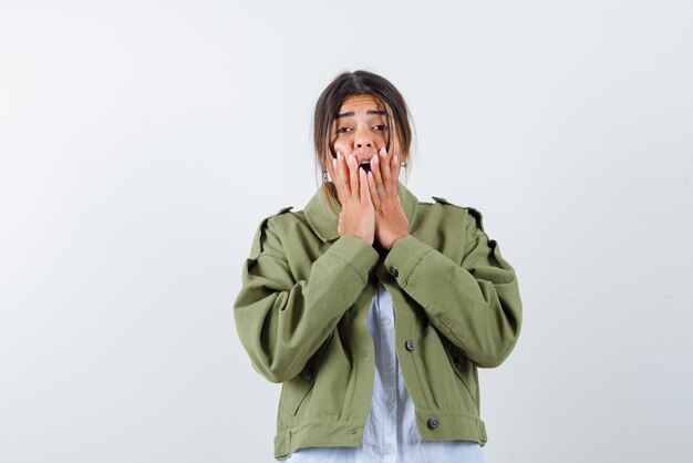 Young woman covering her mouth with hands on white background