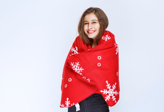 young woman covering herself with a red warm blanket.