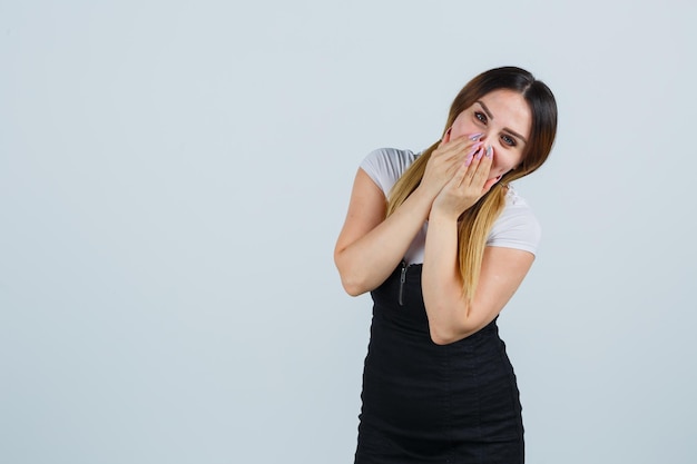 Giovane donna che copre la bocca con le mani mentre sorride