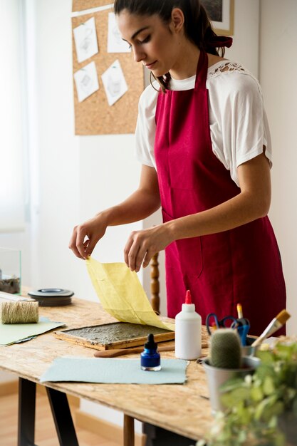 黄色の布で紙パルプを覆う若い女性