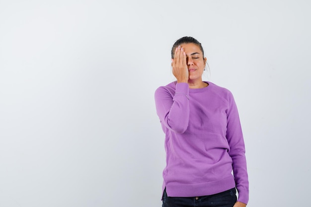 Young woman covering part of face with hand and looking serious