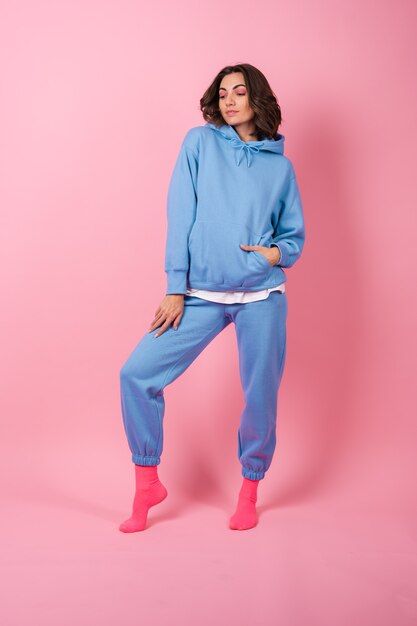 Young woman in a cozy suit on fleece, hoodie and pants, on pink