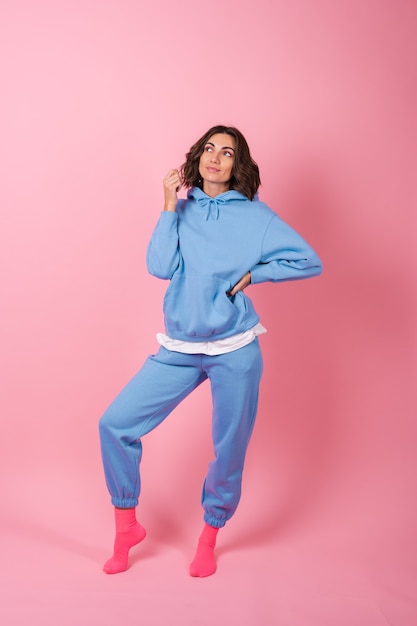 Young woman in a cozy suit on fleece, hoodie and pants, on pink