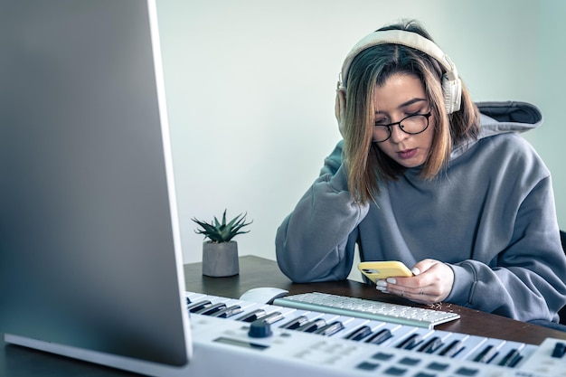 Молодая женщина создает музыку с помощью музыкальной клавиатуры и компьютера.