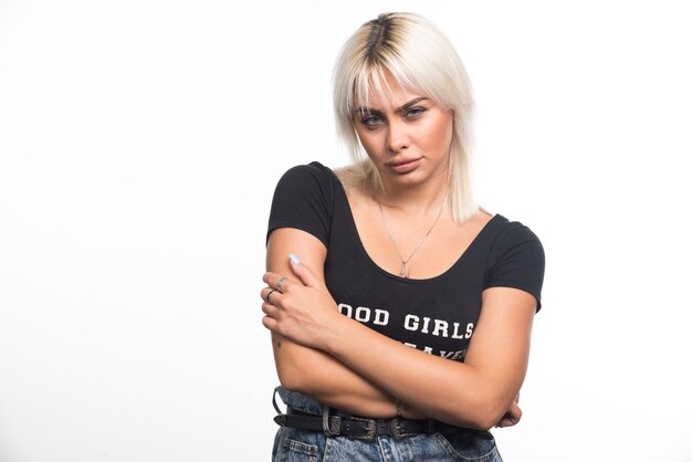 Young woman crossing her arms on white wall.