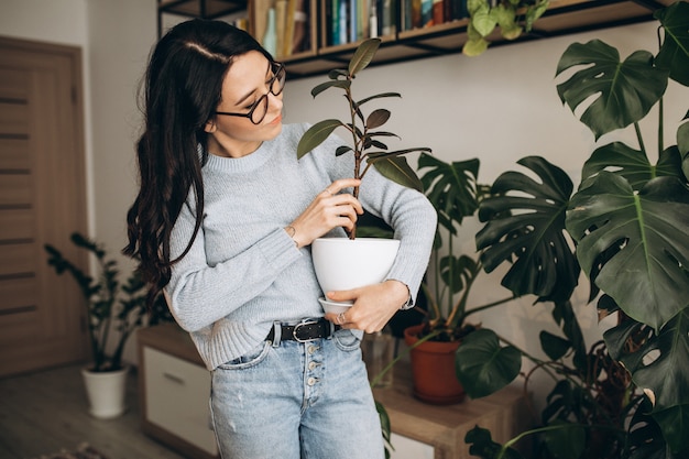 Free photo young woman cultivating plants at home