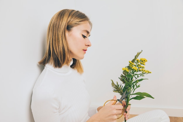 Free photo young woman cutting flowers with scissors