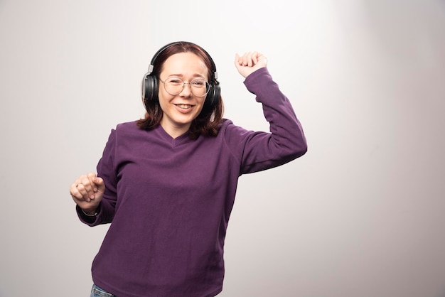 Young woman dancing and listening music in headphones on a white. High quality photo