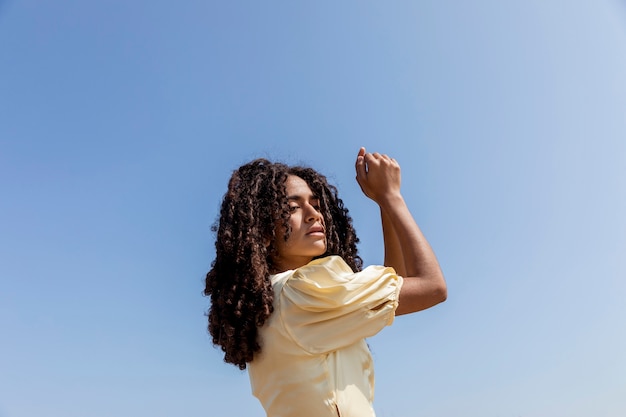Бесплатное фото Молодая женщина танцует на фоне неба