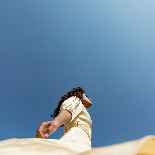 Young woman dancing on sky background