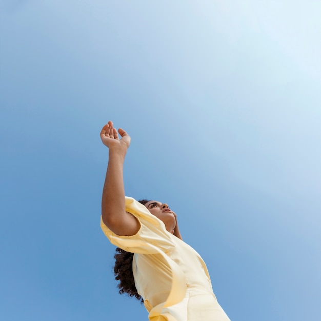 Foto gratuita giovane donna che balla sul fondo del cielo