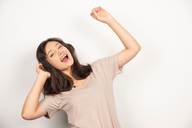 Young woman dancing with hands up on white background.