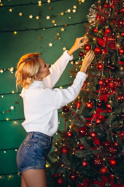 若い女性のクリスマスツリーを飾ること