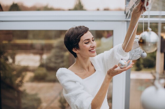 Young woman decorating house with christmas toys