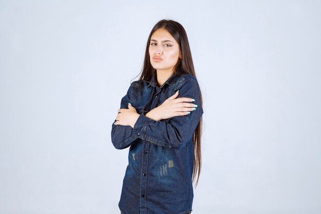 Young woman in denim shirt crossing hands and feeling cold