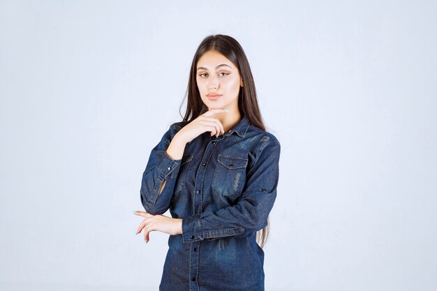 Молодая женщина в джинсовой рубашке дает нейтральные позы без реакции
