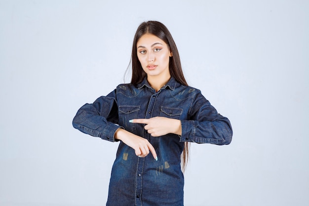 Giovane donna in camicia di jeans che punta al suo tempo