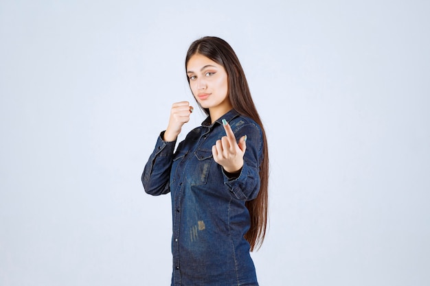 Giovane donna in camicia di jeans che punta alla persona di fronte a lei