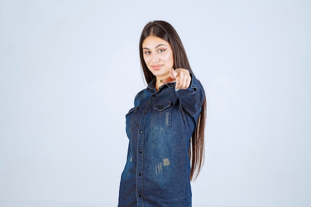 Young woman in denim shirt pointing at the person in front of her