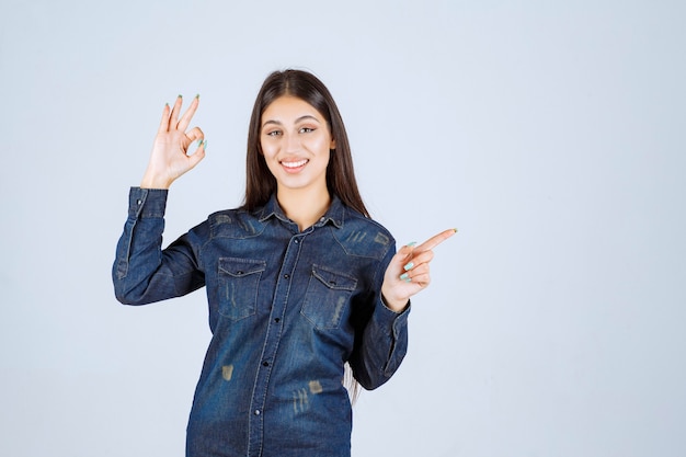 Young woman in denim shirt pointing at the right side