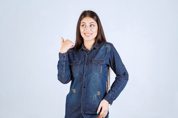Молодая женщина в джинсовой рубашке, указывая на что-то позади