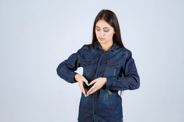 Young woman in denim shirt sending love