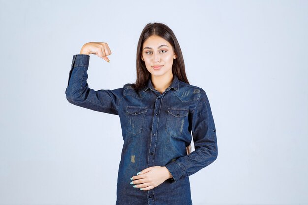 Young woman in denim shirt showing her arm muscles