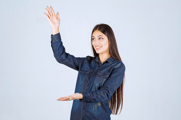 Young woman in denim shirt showing the measures of a product