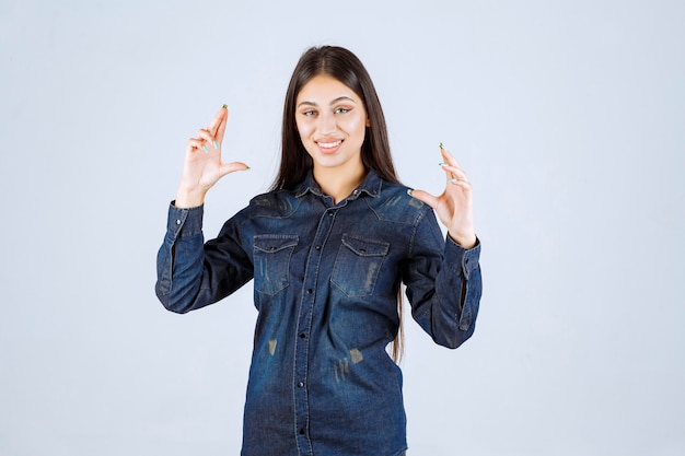 Foto gratuita giovane donna in camicia di jeans che mostra le misure di un prodotto