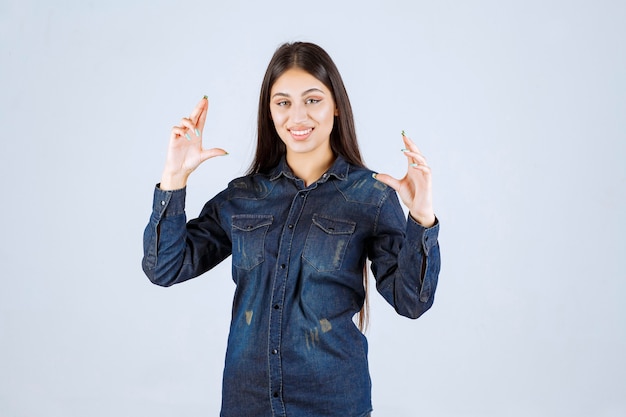 Young woman in denim shirt showing the measures of a product
