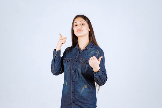 Молодая женщина в джинсовой рубашке показывает положительный знак рукой
